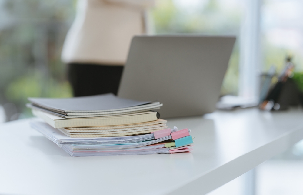 Stacked,Notebooks,And,Laptop,On,White,Desk